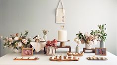 a table topped with vases filled with flowers next to candles and pictures on wooden trays