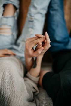 two people sitting next to each other with their hands on the ground and one person holding something