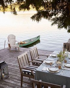 a boat is docked on the water next to a table set with place settings for four