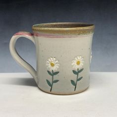 a coffee cup with daisies painted on it