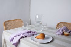 two pears are sitting on a plate next to a glass of water and some napkins