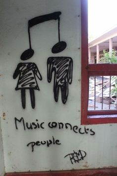 a graffiti on the side of a building with music comes people written in black and white