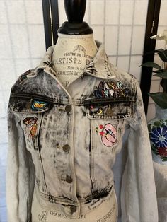 an old jean jacket with patches and buttons on the back, sitting on a mannequin