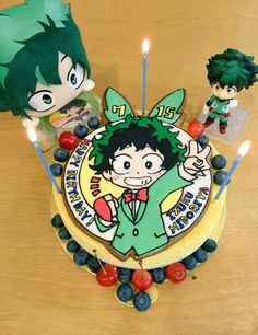 a birthday cake with two figurines on it and candles in the shape of children's faces