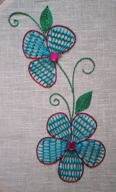 two blue flowers with green leaves on a white cloth background are embroidered onto the fabric