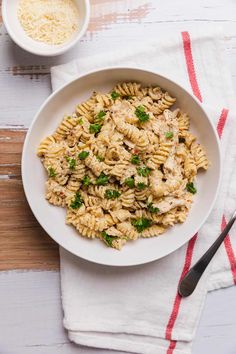 a white bowl filled with pasta and parsley on top of a red and white towel