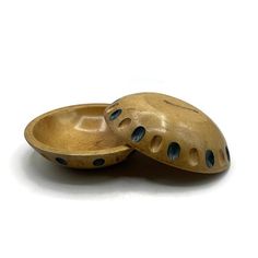 two wooden bowls sitting next to each other on a white surface with holes in them