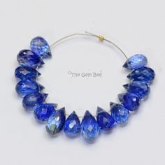 a bracelet made with blue glass beads on a white background and the words true gems bee written below it