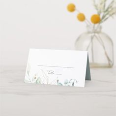 a table card with flowers in a vase behind it