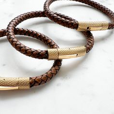 Crafted with braided natural leather and accented with gold stainless steel hardware, our Bourbon Leather Gold Men's Bracelet adds the perfect touch of sophistication to any outfit. The snap closure ensures a secure fit, and with three sizes available, there's a perfect fit for everyone. Elevate your style with this timeless accessory. Comes boxed. Available in three sizes: Small 7.5”, Medium 8.5”, Large 9.25”. Imported. Real Leather. Non toxic design. Gold Leather Bracelet With Brass Hardware, Modern Gold Leather Bracelet With Gold-tone Hardware, Luxury Brown Leather Everyday Bracelet, Gold Leather Bracelets With Gold-tone Hardware, Gold Leather Bracelets For Everyday Use, Everyday Gold Leather Bracelets, Adjustable Leather Bracelets With Gold-tone Hardware, Adjustable Leather Bracelet With Gold Clasp, Brown Leather Bracelets With Brass Hardware