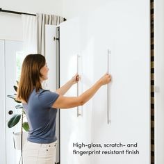 a woman is placing magnets on the wall to keep her from getting stuck in