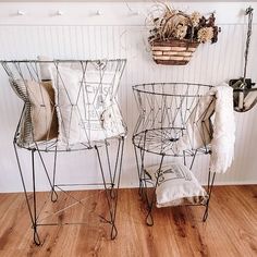 two wire baskets are sitting on the floor in front of a wall with hanging plants