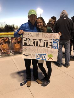 a man and woman standing next to each other holding a sign