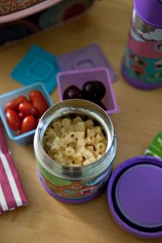 a can filled with macaroni and cheese on top of a table next to plastic containers