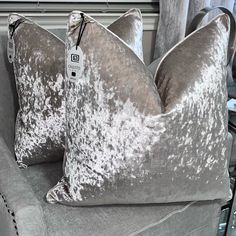 two gray velvet pillows on a grey couch