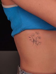 a woman's stomach with a small tattoo on the side of her belly and flowers