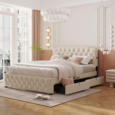 a white bed sitting on top of a hard wood floor next to a large window