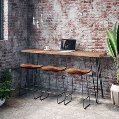 three stools and a table in front of a brick wall with a laptop on it