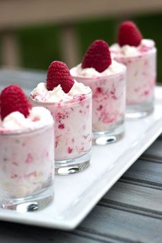 small desserts with raspberries and whipped cream are on a white platter