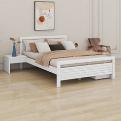 a white bed sitting on top of a hard wood floor next to a painting hanging above it