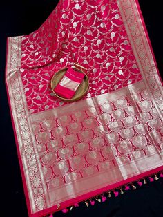 Luxurious Banarasi Semi Pure Mashru silk, renowned for its rich texture and lustrous sheen. The mashru weave combines the elegance of silk, ensuring a graceful drape that feels as good as it looks.  A true masterpiece that seamlessly blends traditional craftsmanship with contemporary flair. Featuring a rich Hot Pink Color, this saree is perfect for special occasions where you want to make a statement. Item : Saree Color : Hot Pink  Base Fabric : Handloom Banarasi Semi Pure Mashru Saree Blouse piece : Comes with Blouse piece Blouse material : Handloom Banarasi Mashru Saree Fall & Edging (Yes/No) : Yes Disclaimer -: - Color variation is possible due to various reasons like phone or desktop setting, resolution etc. Please don't hold us responsible. Our aim is to put the exact color of the Sar Silver Art Silk Dupatta With Cutdana, Silver Raw Silk Dupatta For Diwali, Silver Saree With Dupatta For Navratri, Silver Traditional Wear With Zari Work For Navratri, Silver Traditional Wear With Dupatta For Festive Season, Traditional Silver Lehenga For Festivals, Silver Festive Traditional Wear With Dupatta, Festive Silver Traditional Wear With Dupatta, Silver Traditional Wear For Celebration