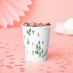 a paper cup filled with ice cream on top of a pink table next to stars