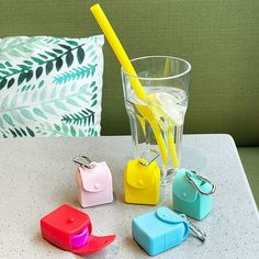 four different colored plastic objects sitting on a table next to a glass with a yellow straw