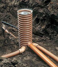 a stack of springs and tubes sitting on top of the ground next to a pile of dirt