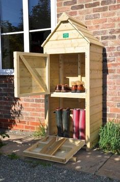 a potting shed is built into the side of a brick building and has rain boots in it