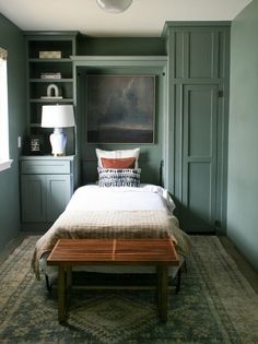 a bedroom with green painted walls and a large painting on the wall above the bed