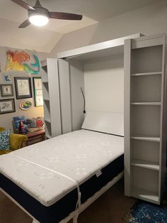 a mattress is in the middle of a room with shelves and pictures on the wall