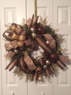 a christmas wreath hanging on the front door with gold and silver ornaments around it's edges