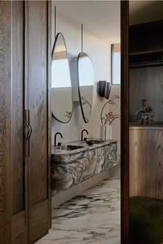 a bathroom with marble counter tops and wooden cabinets in the corner, along with an oval mirror on the wall