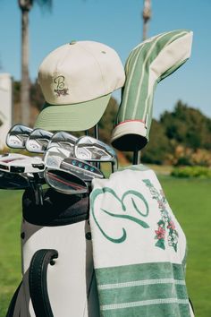 a golf bag and hat sitting on top of a green grass covered golf course with palm trees in the background