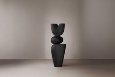 a tall black vase sitting on top of a white floor next to a wall and window