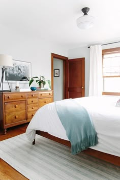 a bedroom with a bed, dresser and window