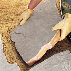 a man is working on some kind of rock with his gloved hand and hammer