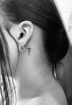 a woman's ear with a small cross tattoo on her left behind the ear