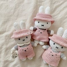 three crocheted stuffed animals in pink outfits