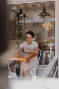 a woman sitting at a table in front of a window