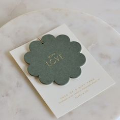 a white plate topped with a card and a green flower on it's side