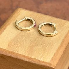 10KT yellow gold genuine ruby huggie hoop earrings. Ruby is the birthstone for July Babies! Also available in emerald. Length: 8mm Diameter: 8mm Thickness: 1.5mm Weight: 1.03 grams Stamped 10K 10K solid gold Latch backs One pair (16) 1.5mm genuine, prong set, round rubies Can also do in ruby Gold Earrings With Ruby Birthstone, Gold Ruby Earrings With Birthstone, Gold Ruby Round Earrings, Anniversary Round Lab-created Ruby Earrings, Luxury Ruby Round Earrings, Panther Jewelry, White Gold Bracelet, Rose Gold Pendant, White Gold Necklaces