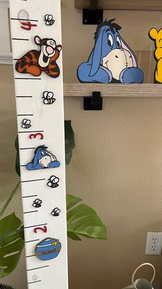 a growth chart with winnie the pooh and tigger on it next to a potted plant