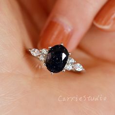 a woman's hand holding a black and white diamond ring