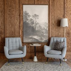 two chairs and a table in front of a painting