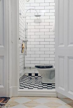 an open door leading to a bathroom with black and white tiles