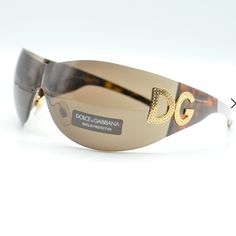 Vintage 2000s Shield Sunglasses By Dolce & Gabbana Featuring A Mirrored Wraparound Rounded Lens In Silver With The Iconic Dg Logo Made In Italy. Brand New In Excellent Condition The Case Itself Has Scratches On It. Not Sure Why The Case Would Peel In Storage. I Checked Other Listings/ It Seems Others Have Done This. Crystals Are All In Tact Brand New Never Worn Just Stored In My Dresser. Right Lense Has Tiny Scratch In Front. See Pictures Dolce & Gabbana Dg6036b Overall Width: 140mm - 5,51 Inche Elegant Brown Shield Sunglasses With Tinted Lenses, Designer Shield Sunglasses For Summer, Dg Logo, Shield Sunglasses, Women Sunglasses, Vintage 2000s, Sunglasses Accessories, Sunglasses Women, Dresser