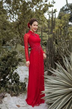 a woman in a red dress standing next to cactus