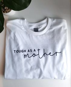 This Tough as a Mother short sleeve shirt is 100% cotton and unisex sizing. Unisex Cotton Shirt With Funny Text, Basic Cotton Shirt With Funny Text, Unisex Cotton Shirt With Text Print, Cotton Short Sleeve Shirt With Funny Text, White Print Short Sleeve Cotton Shirt, Spring Cotton Shirt With Funny Text, Cotton T-shirt With Funny Text For Everyday, Everyday Cotton T-shirt With Funny Text, Spring Cotton T-shirt With Funny Text