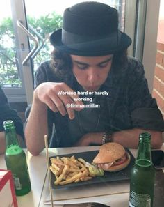 a man sitting at a table in front of a plate of fries and a sandwich